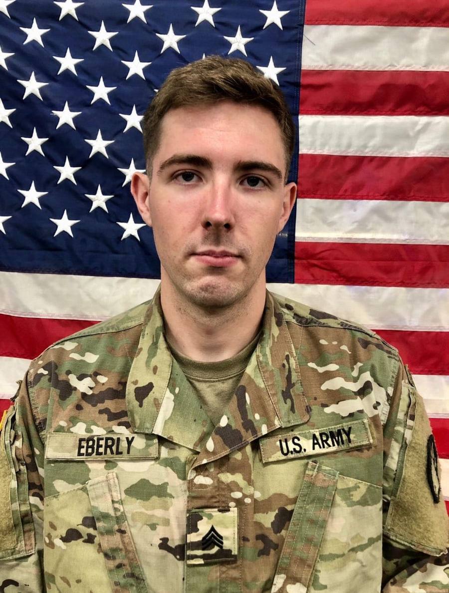 Andrew Eberly in Army uniform in front of an American flag